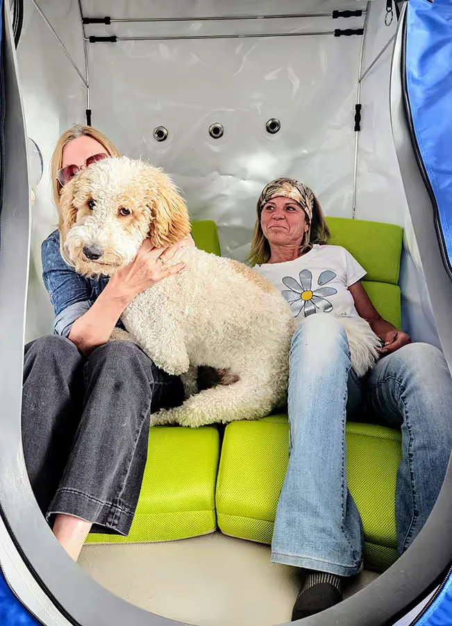 Frau mit Hund entspannt in einer blueO2 Sitzkammer